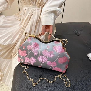 Detail of floral embroidery on grey handbag with golden metal handle and chain
