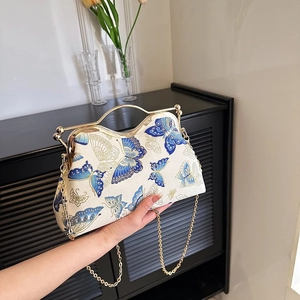 Detail of vintage cream fabric handbag with blue butterfly prints and gold metal handle