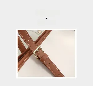 Détail de la bandoulière en cuir marron avec coutures blanches et boucle dorée