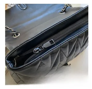 Détail d'une fermeture éclair fluide sur un sac matelassé noir avec bandoulière chaîne