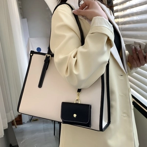 Détail du grand sac cabas crème avec coutures noires contrastées et mini pochette pendante