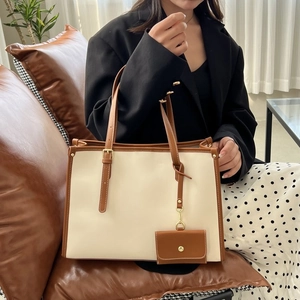Détail d'un grand sac cabas bicolore crème et marron avec finitions dorées chic