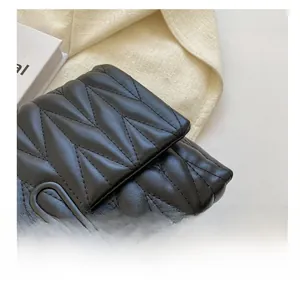 Gros plan sur les surpiqûres en V noires et la boucle chaîne mate du petit sac carré