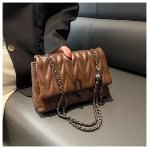 Détail du sac en cuir matelassé marron foncé avec chaîne noire et boucle en forme de U