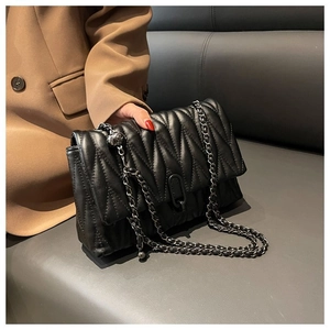 Détail de la texture matelassée noire avec chaîne métallique élégante sur le sac bandoulière