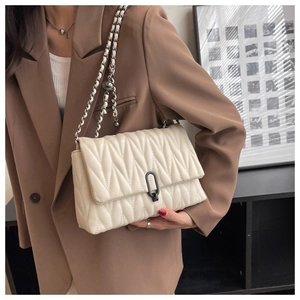 Vue détaillée du sac à main matelassé beige avec bandoulière sur un blazer marron