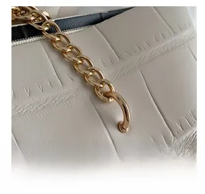 Macro detail of beige stone pattern tote bag with gold chain and reinforced metal ring