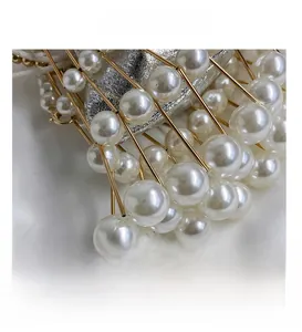 Macro detail of hand-woven crossbody bag featuring large white faux pearls and gold frame