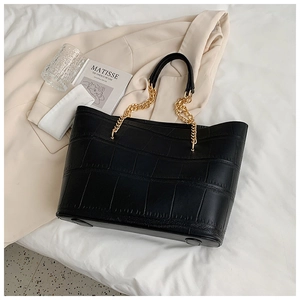 Detailed view of black crocodile pattern tote bag with gold chain and bottom metal feet