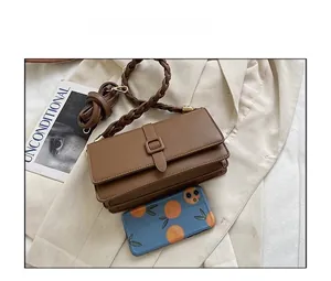 Détail d'un sac bandoulière vintage en cuir marron avec poignée tressée et longue sangle