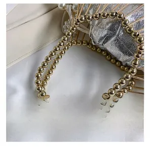 Detail of golden birdcage evening bag showing metal handle and pearl embellishments