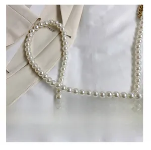 Close-up of elegant pearl shoulder strap with high-luster round beads on neutral fabric