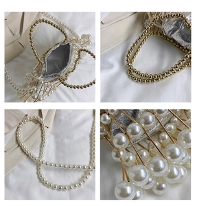 Detail of beaded evening bag featuring gold metal cage and large pearls on white fabric