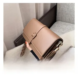 Détail d'un sac à main tendance marron avec poignée tressée et boucle dorée sur tissu