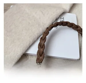 Détail d'un sac à main en cuir marron foncé avec une poignée en cuir tressé classique