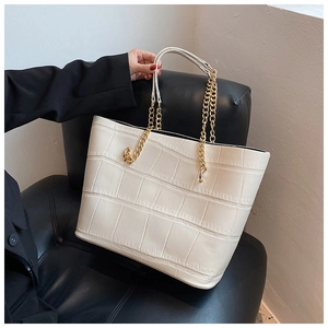 Close-up of white tote bag featuring crocodile texture and gold metal chain strap