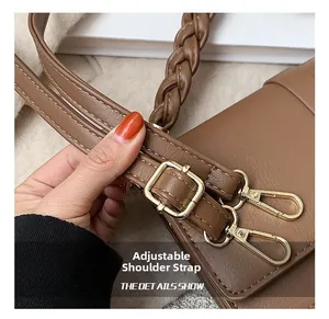 Détail de la bandoulière en cuir marron avec boucle en métal doré et surpiqûres