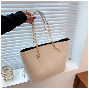 Close-up of white tote bag featuring crocodile pattern texture and gold chain straps