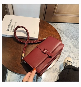 Détail du sac carré en cuir bordeaux avec boucle décorative et bandoulière tressée