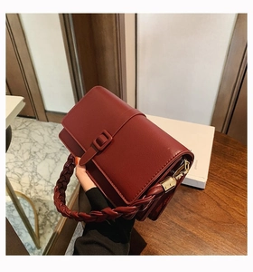 Détail du sac à main bordeaux avec poignée tressée épaisse et boucles en métal doré