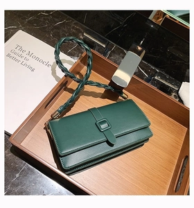 Vue détaillée d'un sac à main en cuir vert foncé avec bandoulière tressée et boucle carrée