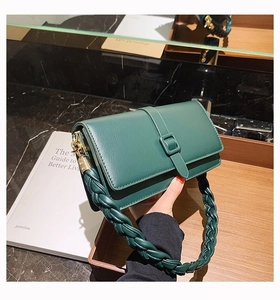 Détail d'un sac à main en cuir vert foncé avec poignée tressée et boucles en métal doré