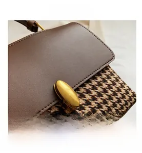 Detail of vintage houndstooth and brown leather bag with golden oval twist lock