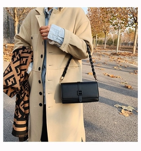 Détail d'un sac bandoulière en cuir noir avec sangle tissée sur fond d'automne urbain