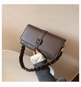 Détail d'un sac à main marron foncé avec poignée tressée épaisse et texture cuir