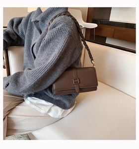Détail du sac à main en cuir marron foncé avec bandoulière tressée et boucles dorées