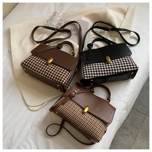 Detail view of plaid patterned satchel bags with leather trim and gold metal lock buckles