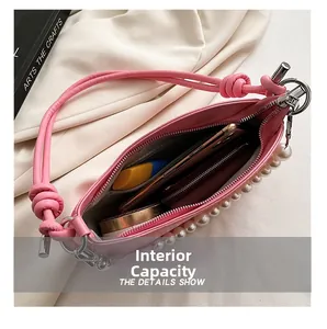 Interior capacity of pink leather shoulder bag showing cosmetics and pearl decoration
