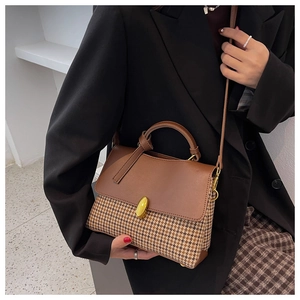 Detail of vintage plaid handbag featuring brown leather flap and gold twist-lock closure