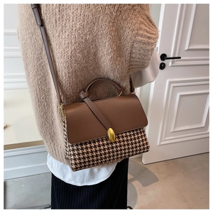 Detail of vintage houndstooth handbag with brown leather flap and gold metal buckle