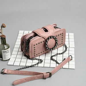 Detail of pink chain bag with three zippers and large rhinestone buckle