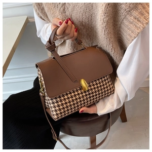 Detail of checkered shoulder bag with golden lock and stylish knotted leather handle