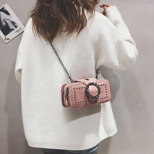 Pink mini crossbody bag with rhinestone ring buckle and chain strap on white knitwear
