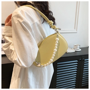 Detail of light yellow crescent bag with decorative faux pearl chain and matte PU leather