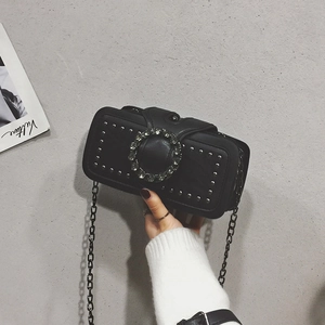 Detail of mini black crossbody bag with rhinestone buckle and silver stud accents