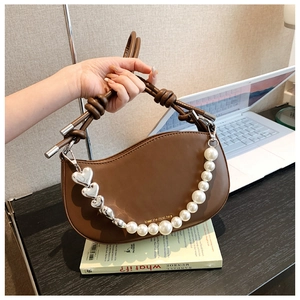 Detail of dark brown crescent bag with pearl chain and silver heart accents