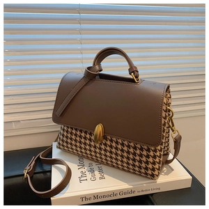 Detail of vintage houndstooth plaid handbag with brown leather flap and gold oval buckle