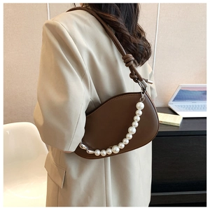 Detailed view of brown crescent shoulder bag featuring large pearl chain and knotted strap