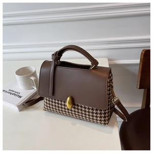Detail of vintage plaid handbag with brown leather flap and golden twist lock closure