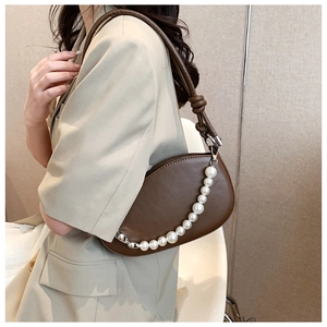 Detail of dark brown leather shoulder bag featuring decorative white pearl chain and knotted strap