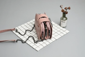 Detail of pink multi-layer crossbody bag with gunmetal chains on minimalist grid