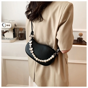 Detail of black leather half-moon bag featuring pearl and silver heart accent chains
