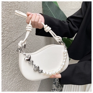 Detail of white crescent bag featuring large pearls and silver heart-shaped pendants