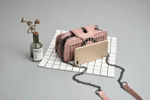 Close-up of pink mini chain bag featuring silver rivets and rhinestone buckle decoration