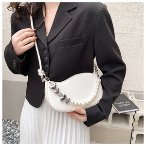 White hobo bag featuring silver heart ornaments and elegant pearl chain shoulder strap detail
