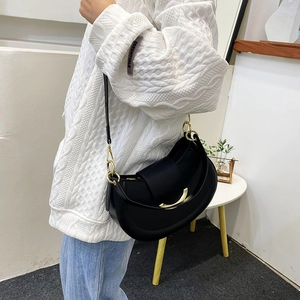 Close-up of black crescent shoulder bag with a curved gold metal clasp and leather strap